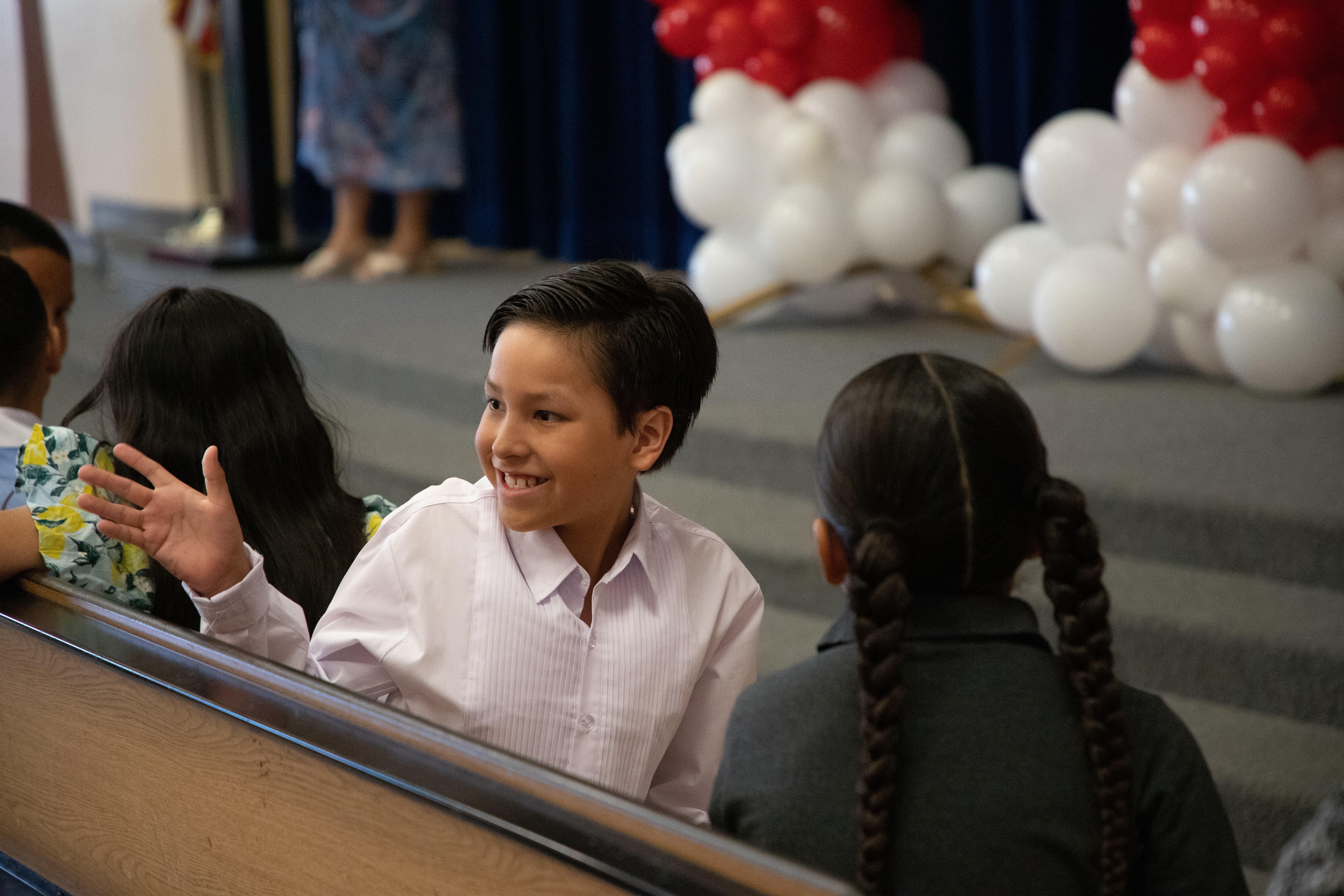 A little boy smiles and turns around to face his family during the ceremony