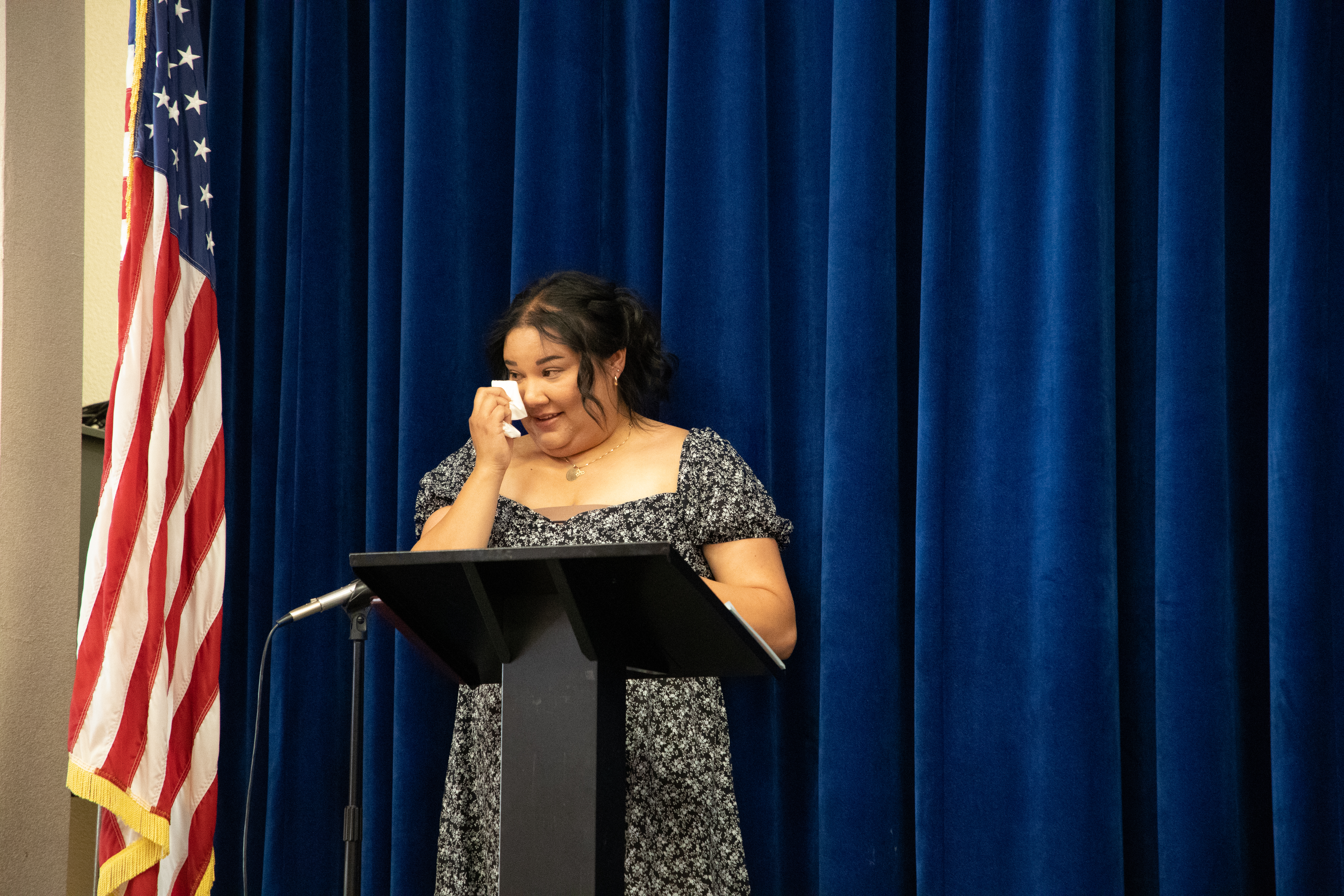 A woman dabs her eyes on stage