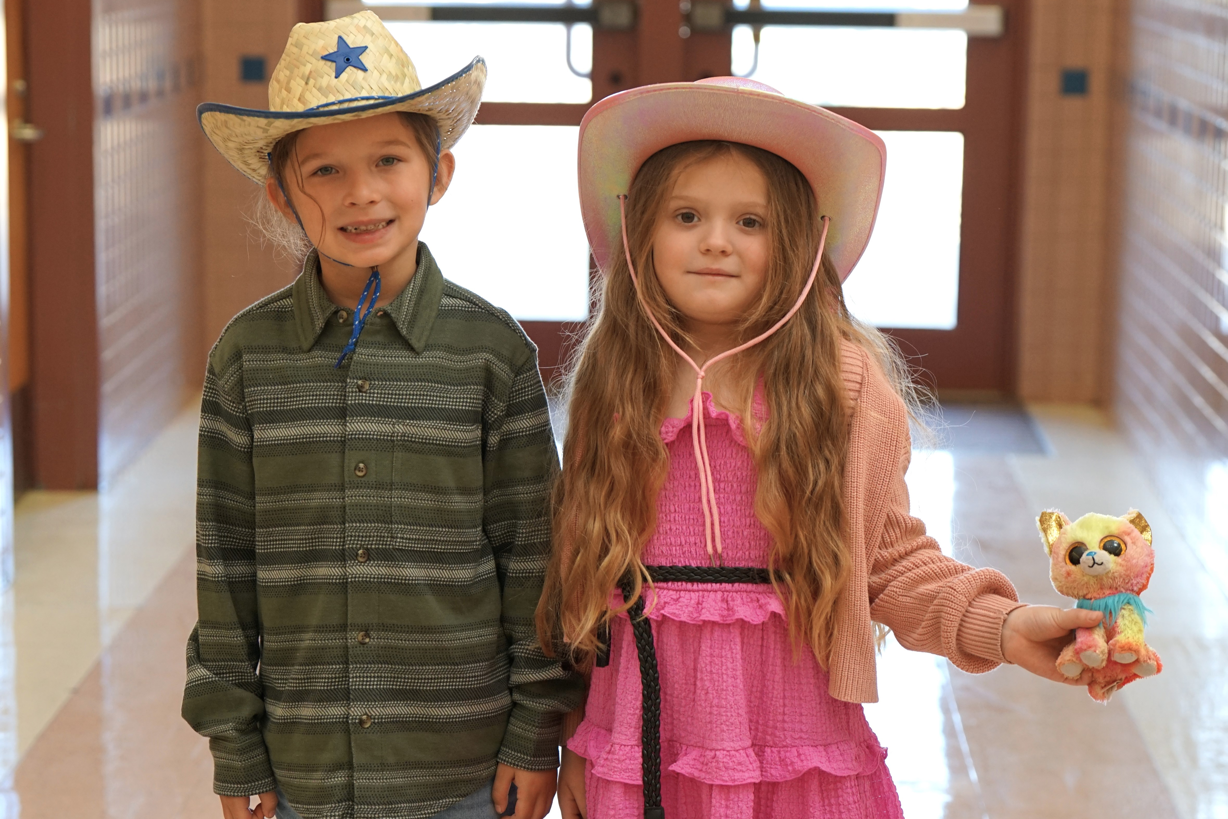 A boy and girl wearing cowboy hats in the hallway