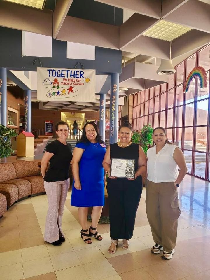Four women smile in the lobby of the school