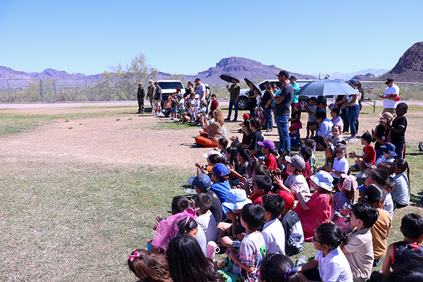 Students sit on the field during the K9 demonstration