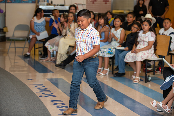 A boy walks across the cafeteria to the stage