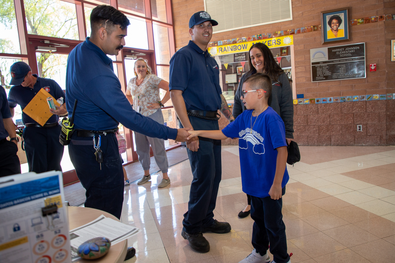 A Drexel Heights Fire Department firefighters shakes a student's hand.